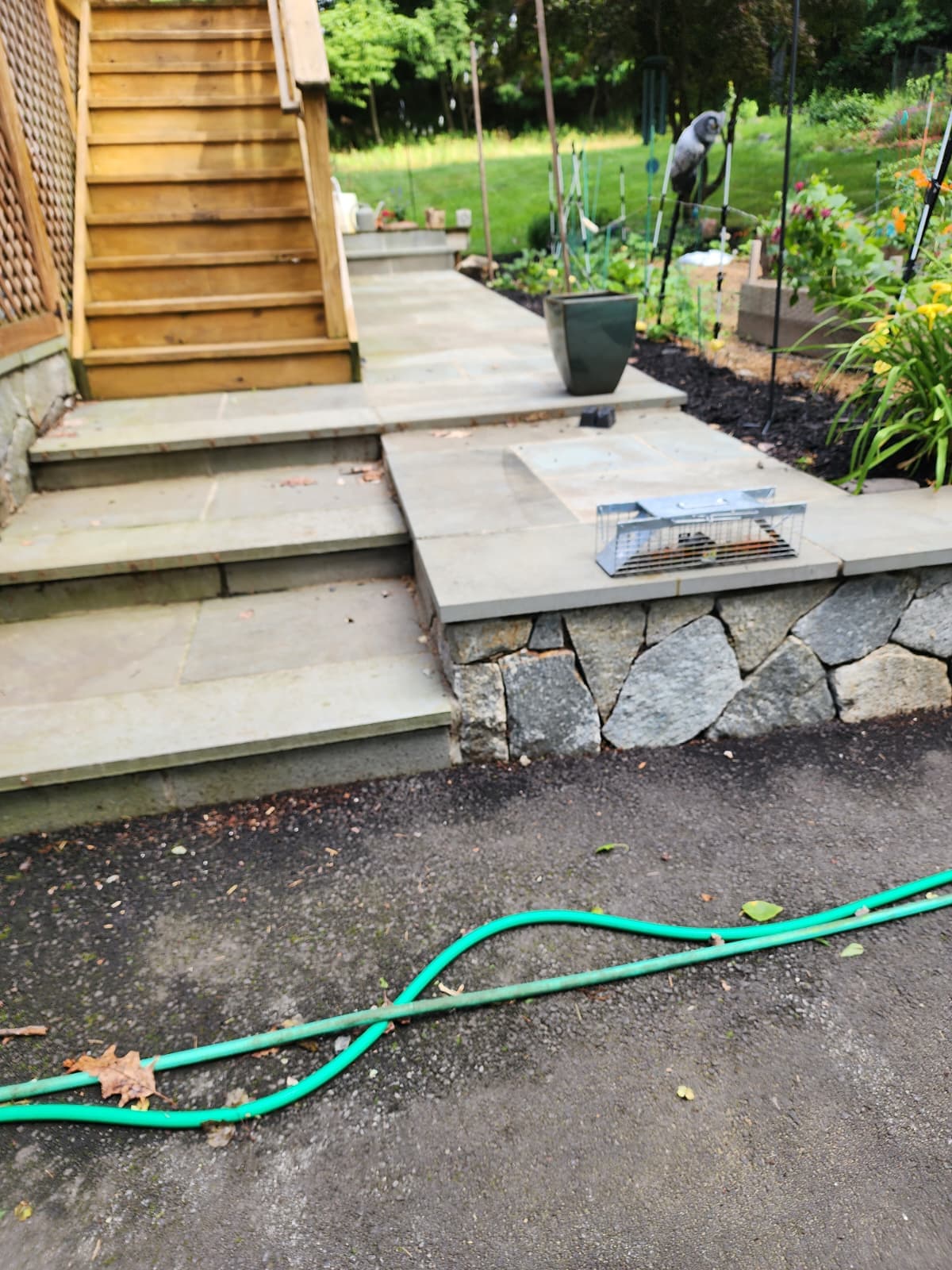 Bluestone patio with a fieldstone retaining wall and stone steps beside a garden