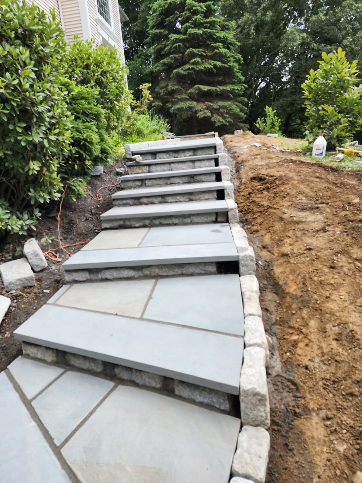 Bluestone steps with granite block risers climbing a landscaped slope