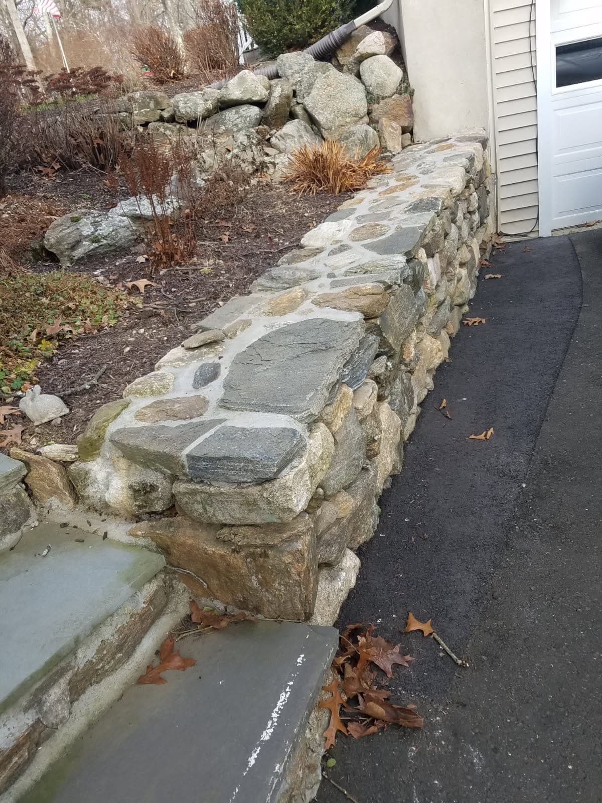 Natural fieldstone retaining wall along a driveway built by Chabla's Construction
