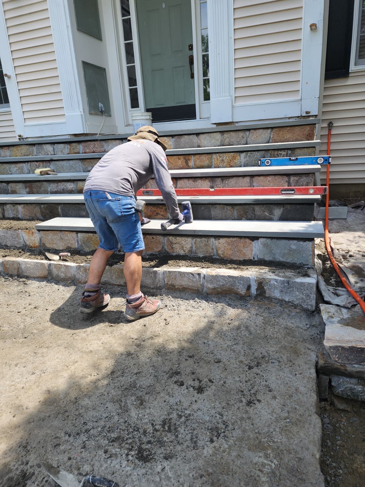 Granite block steps being leveled during a front entrance installation