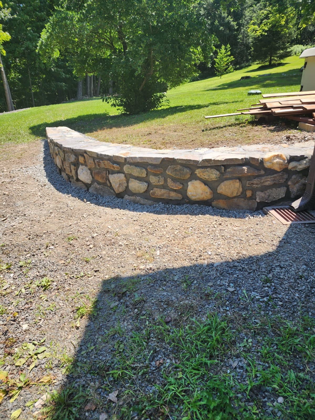 Curved natural stone seat wall set into a backyard landscape