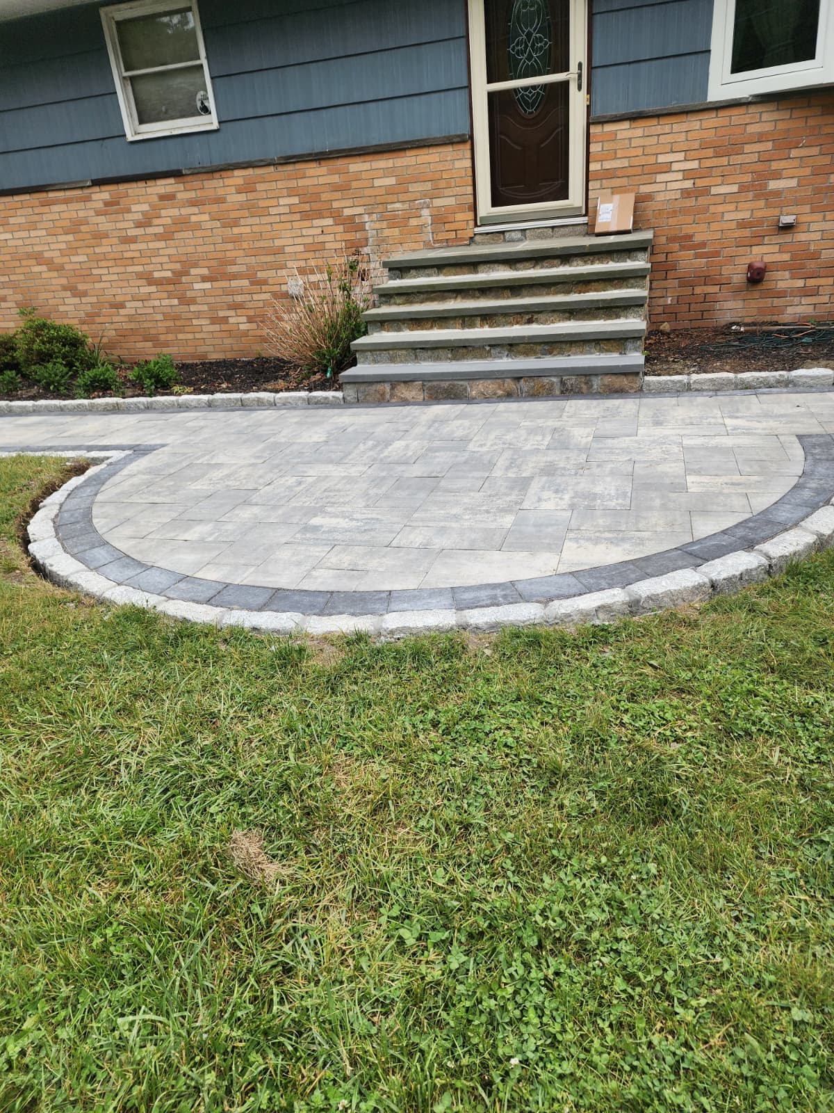 Curved paver patio with a contrasting border at a home entrance