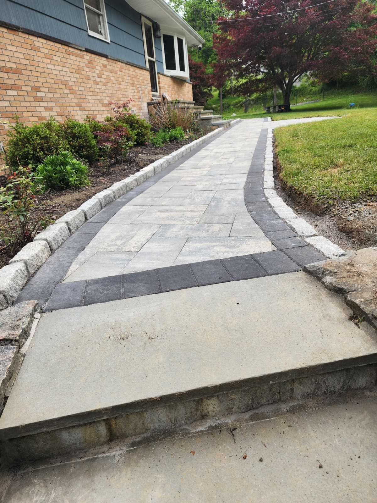 Paver walkway with a contrasting border running alongside a home