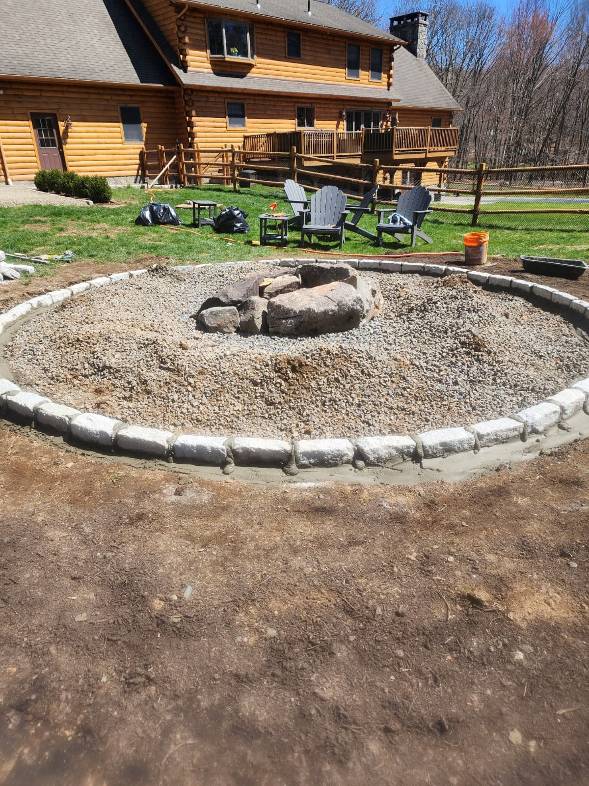 Circular stone fire pit ringed with Belgian block in a backyard